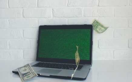 Image of computer with dollar bills flying around it by NeONBRAND on Unsplash