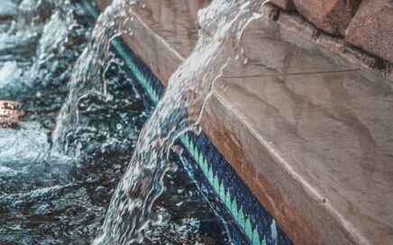 Photo of water running out of a series of pipes next to each other in a wall courtesy Pixabay