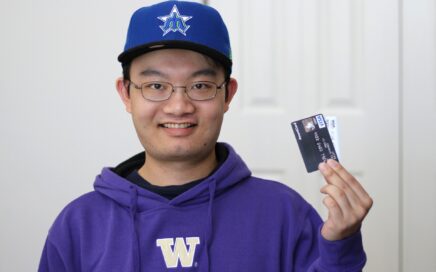 Photo of Asian man in hat holding up credit cards