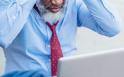 Man with head in hands looking at his laptop computer