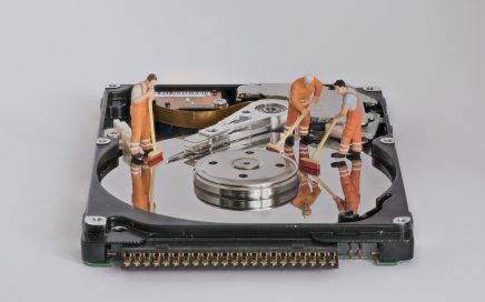Little men standing on top of a hard drive platter with brooms cleaning up the surface