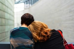 Woman leaning on the shoulder of another while they sit on a bench facing away from the camera courtesy of Transly Translation Agency/Unsplash
