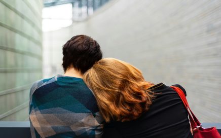 Woman leaning on the shoulder of another while they sit on a bench facing away from the camera courtesy of Transly Translation Agency/Unsplash
