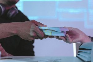 One hand handing packs of money to another hand