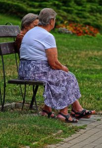 Two women sitting on a park bench talking