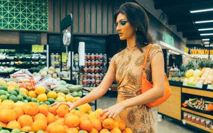 Photo of a high-fashion model looking over fruit in a grocery store courtesy of Rulo Davila - Pexels